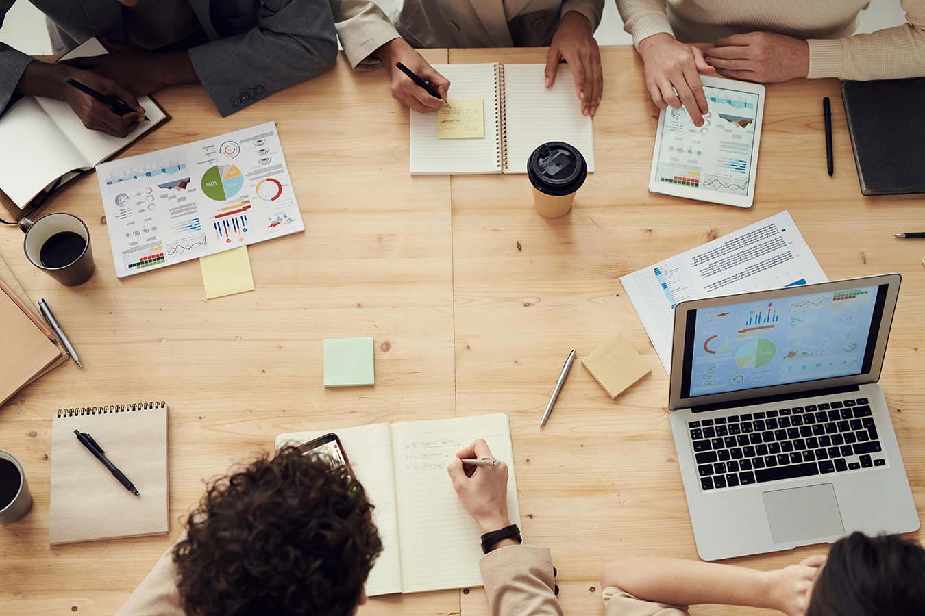 Mehrere Mitarbeitende sitzen an einem hellen Holztisch und besprechen Maßnahmen zu Corporate Sustainability.