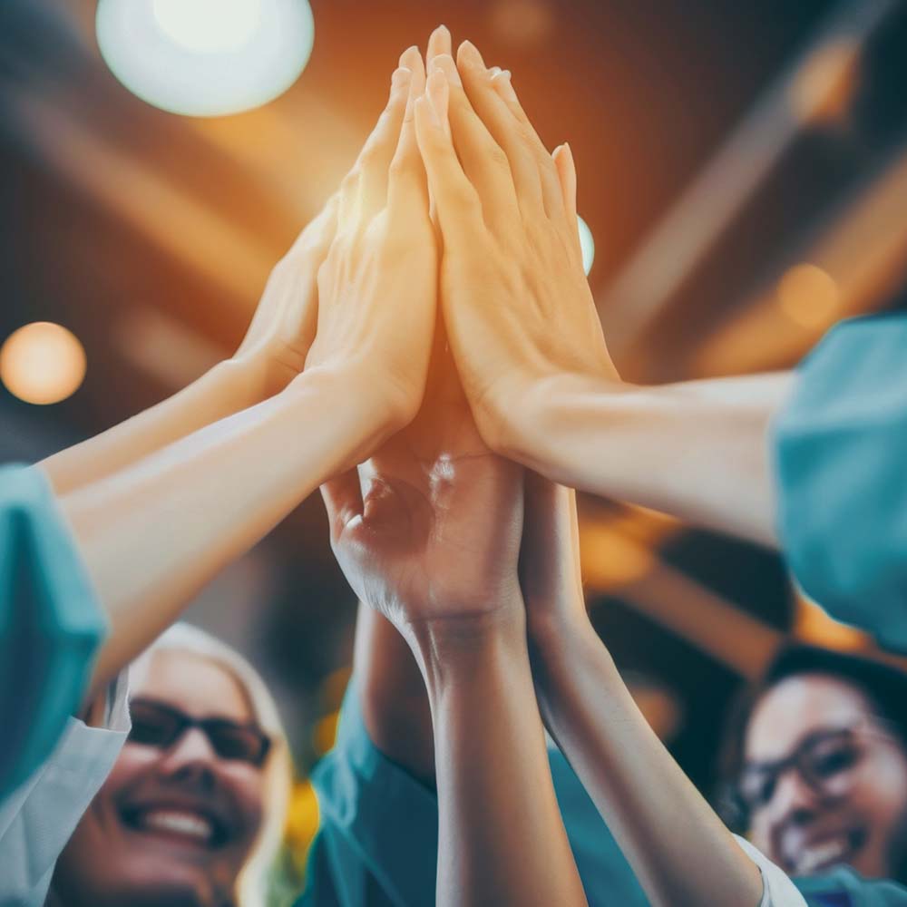 Ein Team von Kollegen klatscht zusammen in die Hände, nachdem die Herausforderungen zum Steigern der Effizienz gemeistert worden sind.