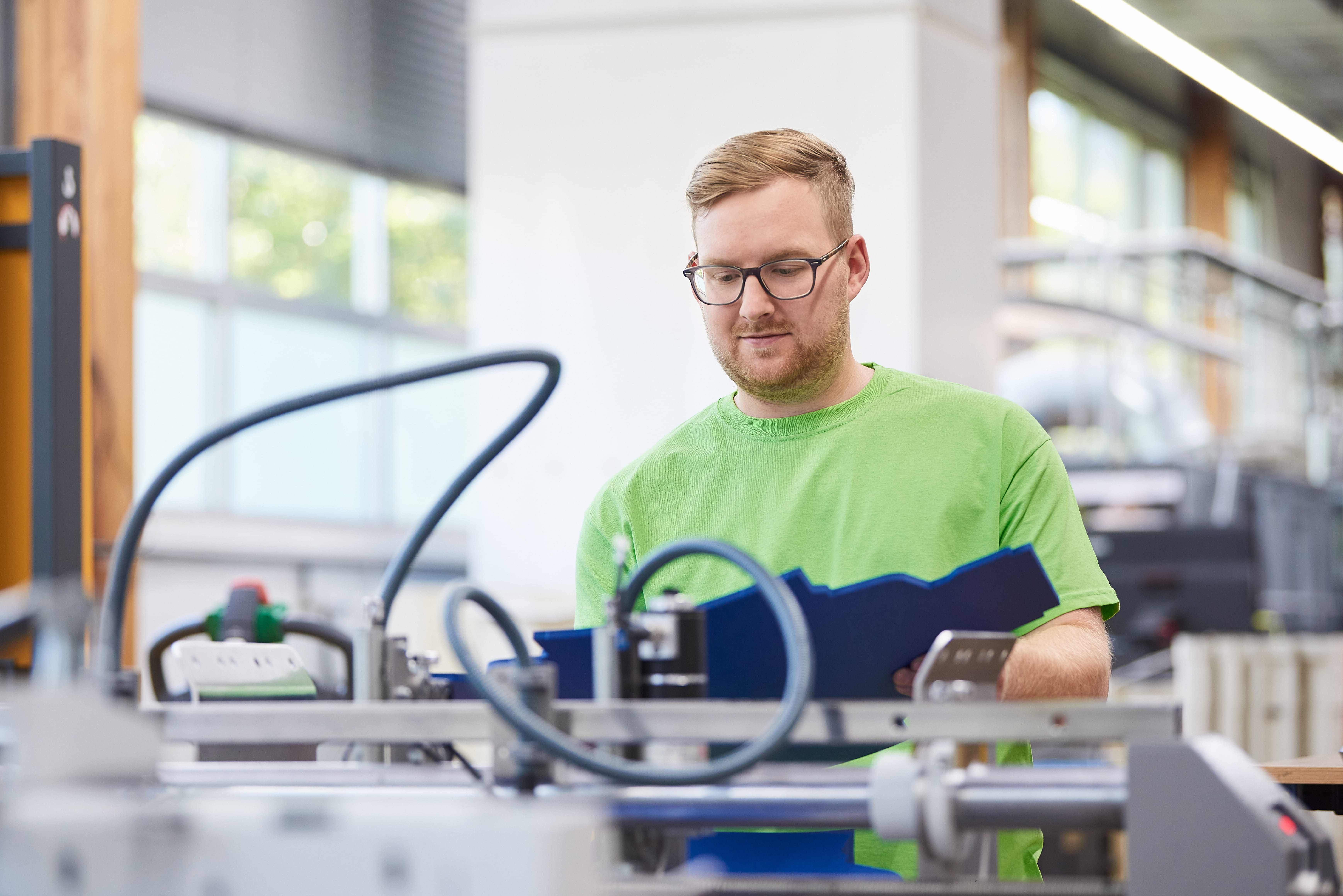 Mann steht in Produktionshalle und prüft Zuschnitt