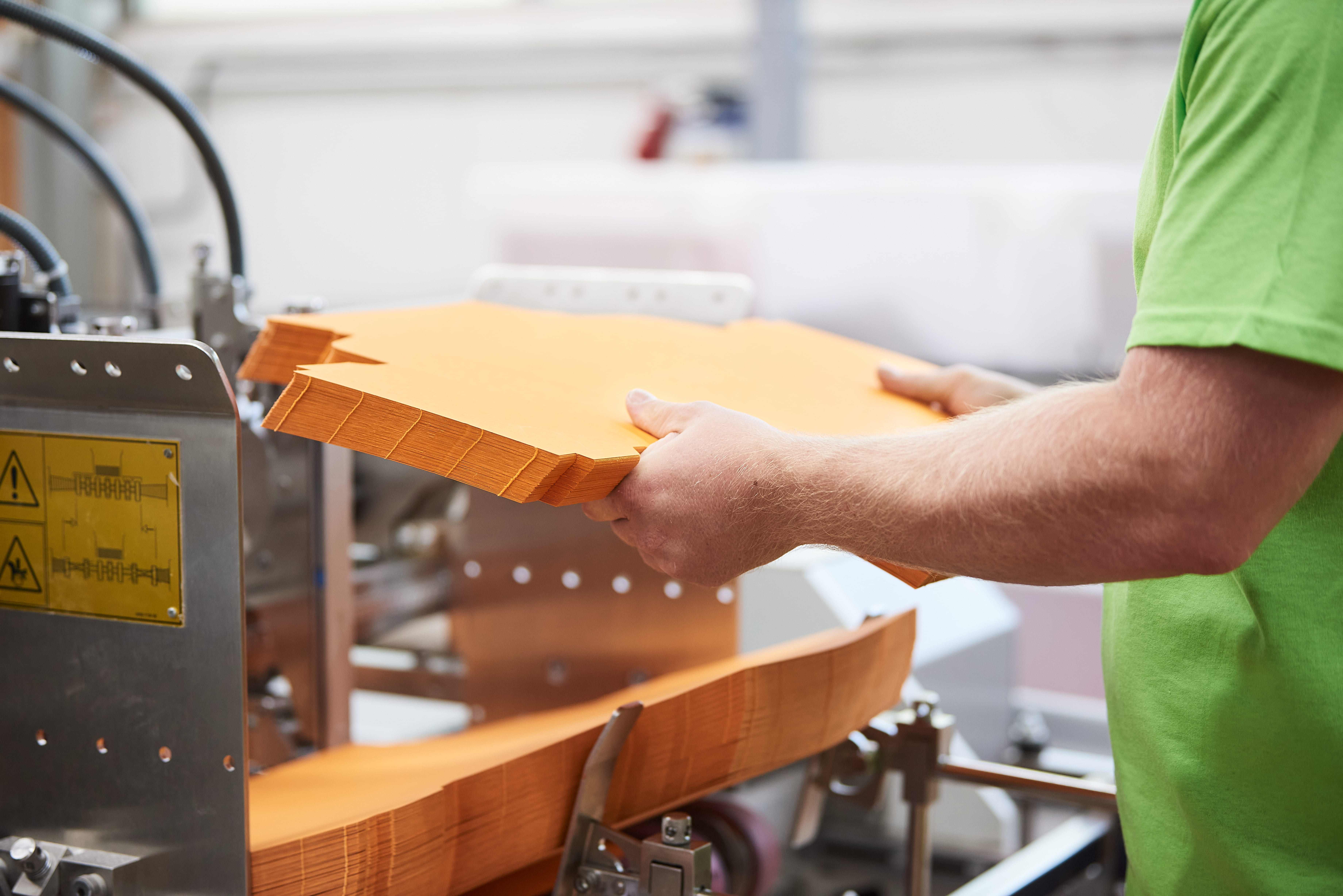 Karton-Zuschnitt wird in die Klebemaschine eingelegt