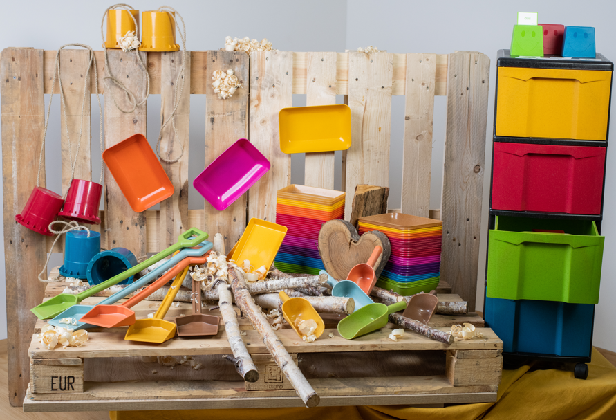 Bunte Produkte wie Schaufeln, Aufbewahrungsboxen und Eimer auf einer Holzpalette angerichtet. 